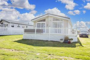 a white house with a white fence in a yard at Luxury 6 Berth Lodge With Wifi At Broadland Sands In Suffolk Ref 20011cv in Hopton on Sea