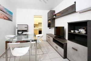 uma cozinha com uma mesa de vidro e cadeiras brancas em Appartamenti Diffusi di Villa Fiorita em Cattolica
