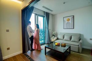 a man and woman standing in a living room looking out the window at MK Riverside Apartment by Haviland in Danang