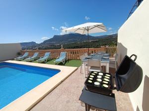 patio ze stołem i krzesłami przy basenie w obiekcie Villa Noemi, con piscina privada w mieście Calpe