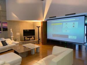 a large screen in a living room with white furniture at 24時間源泉掛け流しGuest House Belle Hakone in Hakone
