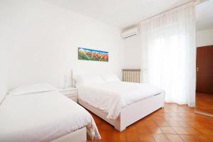 a white bedroom with two beds and a window at Appartamenti Diffusi di Villa Fiorita in Cattolica