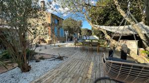 una terraza de madera con una hamaca en un patio en L'Oliveraie d'Eurocentre - Toulouse Nord en Castelnau-dʼEstrétefonds