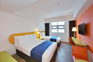 a hotel room with two beds and a desk at Fullon Poshtel Kenting in Kenting