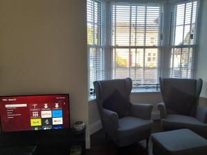 two chairs and a television in a living room with windows at Kirkcudbright Holiday Apartments - Apartment C in Kirkcudbright