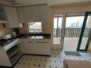 uma cozinha com armários brancos e vista para uma varanda em Lakeview Cannobio Camping & Resort em Cannobio