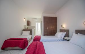 Cette chambre d'hôtel comprend 2 lits avec des draps rouges. dans l'établissement San - Mari Studios, à Laganas