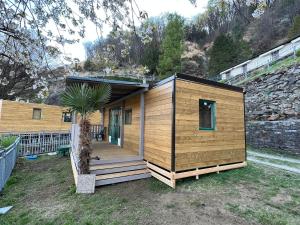 una pequeña casa de madera con una palmera en el patio en Lakeview Cannobio Camping & Resort, en Cannobio