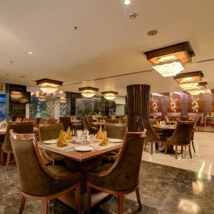 a dining room with tables and chairs in a restaurant at Godwin Haridwar in Haridwār