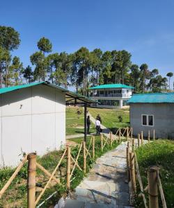 un par de personas de pie junto a un edificio en Nitya Village Retreat, en Chamba