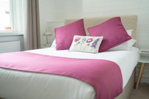 a bed with purple and white sheets and pillows at INNit Marina in Brighton & Hove