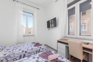 a bedroom with a bed and a desk and windows at Market & Art square place in Rijeka