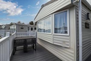 a large deck with a bench on the side of a house at Brilliant 6 Berth Caravan At Broadland Sands Holiday Park In Suffolk Ref 20003cf in Hopton on Sea