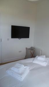 a white bed with two towels on it with a tv on the wall at Buckie - 2 Bed Luxury Apartment in Wick