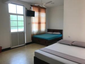 a bedroom with two beds and a window at Hotel Ganthera Kataragama in Kataragama