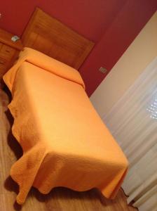 a bed with an orange blanket on top of it at El Ancla in Ponferrada