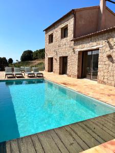 a swimming pool in front of a stone house at Les Demeures de Piana in Piana
