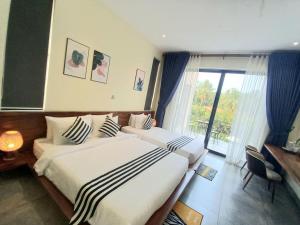 um quarto de hotel com duas camas e uma janela em Kampot Tropical Village em Kampot