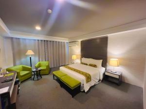 a hotel room with a bed and two green chairs at 88 Courtyard Hotel in Manila