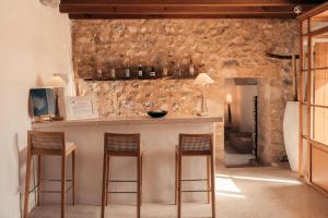 a kitchen with a bar with three stools at Cases de Son Barbassa Hotel & Restaurant in Capdepera