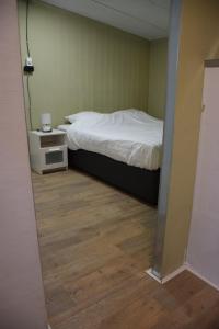 1 dormitorio con 1 cama y suelo de madera en camping family room, en Ter Aar