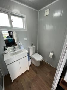 a bathroom with a toilet and a sink and a window at Raglan Seaview Cabin in Raglan