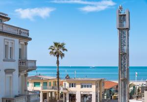 - une vue sur la plage, les bâtiments et un palmier dans l'établissement Hotel Stella Del Mare, à Viareggio