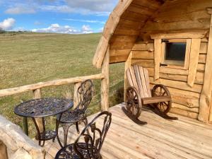 un porche de una cabaña de madera con mesa y sillas en The Prancing Moose, en Ystrad Meurig