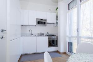 eine weiße Küche mit einer Spüle und einem Herd in der Unterkunft Appartamento Rossini - Volta 4 in Cernobbio