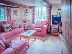 ein Wohnzimmer mit rosa Sofas und einem TV in der Unterkunft The Mansion Cottage in Tetford