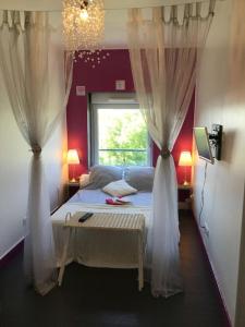 - une chambre avec un lit avec des rideaux et une fenêtre dans l'établissement Maison 6/8pers en Bourgogne, à Mâcon