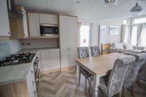 a kitchen and living room with a table and a couch at Stunning Caravan With Full Sea Views At Broadland Sands In Suffolk Ref 20236bs in Hopton on Sea
