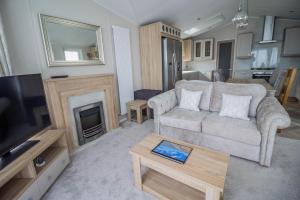 a living room with a couch and a fireplace at Stunning Caravan With Full Sea Views At Broadland Sands In Suffolk Ref 20236bs in Hopton on Sea