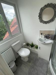 a bathroom with a toilet and a sink and a window at Wembley Rooms in London