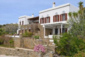 a large white house with a stone wall at Santamare Apartment in Agios Sostis