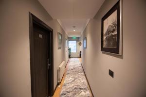 a hallway with a black door and paintings on the walls at Sky View Hotel in Korçë