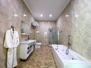 a bathroom with a tub and a toilet and a sink at Wellness Park Hotel Gagra All-Inclusive in Gagra