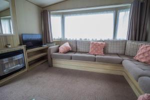 a living room with a couch and a television at Great 8 Berth Caravan In Norfolk Near To Great Yarmouth Ref 20178bs in Hopton on Sea