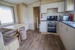 a small kitchen with a table and a stove at Great 8 Berth Caravan In Norfolk Near To Great Yarmouth Ref 20178bs in Hopton on Sea