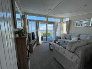 uma sala de estar com dois sofás e uma televisão e janelas em Beautiful Lodge With Full Sea Views At Broadland Sands In Suffolk Ref 20235bs em Hopton on Sea
