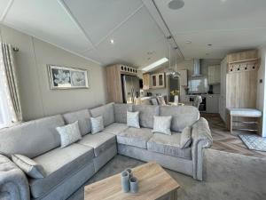 ein Wohnzimmer mit einem großen Sofa und einer Küche in der Unterkunft Beautiful Lodge With Full Sea Views At Broadland Sands In Suffolk Ref 20235bs in Hopton on Sea