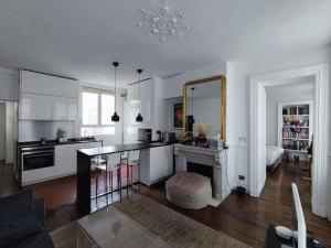biała kuchnia ze stołem i lustrem w obiekcie Air conditioning Paris central stylish apartment w Paryżu