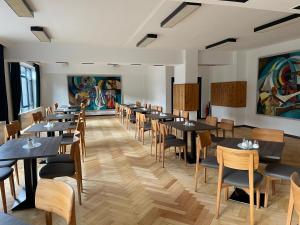 a dining room with tables and chairs and paintings at Olympia Hotel Suhl in Suhl