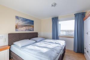 Schlafzimmer mit einem Bett mit blauen Vorhängen und einem Fenster in der Unterkunft Ferienwohnung 8 im Haus Horizont in Cuxhaven
