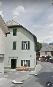 ein weißes Haus mit grünen Rollläden auf einer Straße in der Unterkunft Belavita in Bovec
