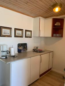 una cocina con armarios blancos y fregadero en JJ Guesthouse Studio 35, en Skagen
