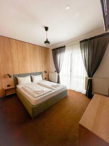 ein Schlafzimmer mit einem Bett und einem großen Fenster in der Unterkunft Vila M 36 in Topliţa