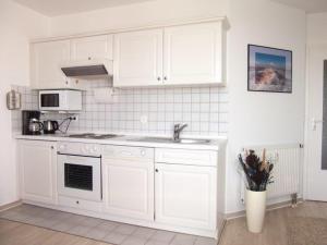 una cucina con armadi bianchi e lavandino di Robbenplate 19 a Cuxhaven