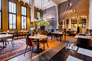 a restaurant with tables and chairs and windows at Post-Plaza Hotel & Grand Café in Leeuwarden