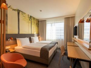 a hotel room with a bed and a desk at Holiday Inn Munich - Leuchtenbergring, an IHG Hotel in Munich